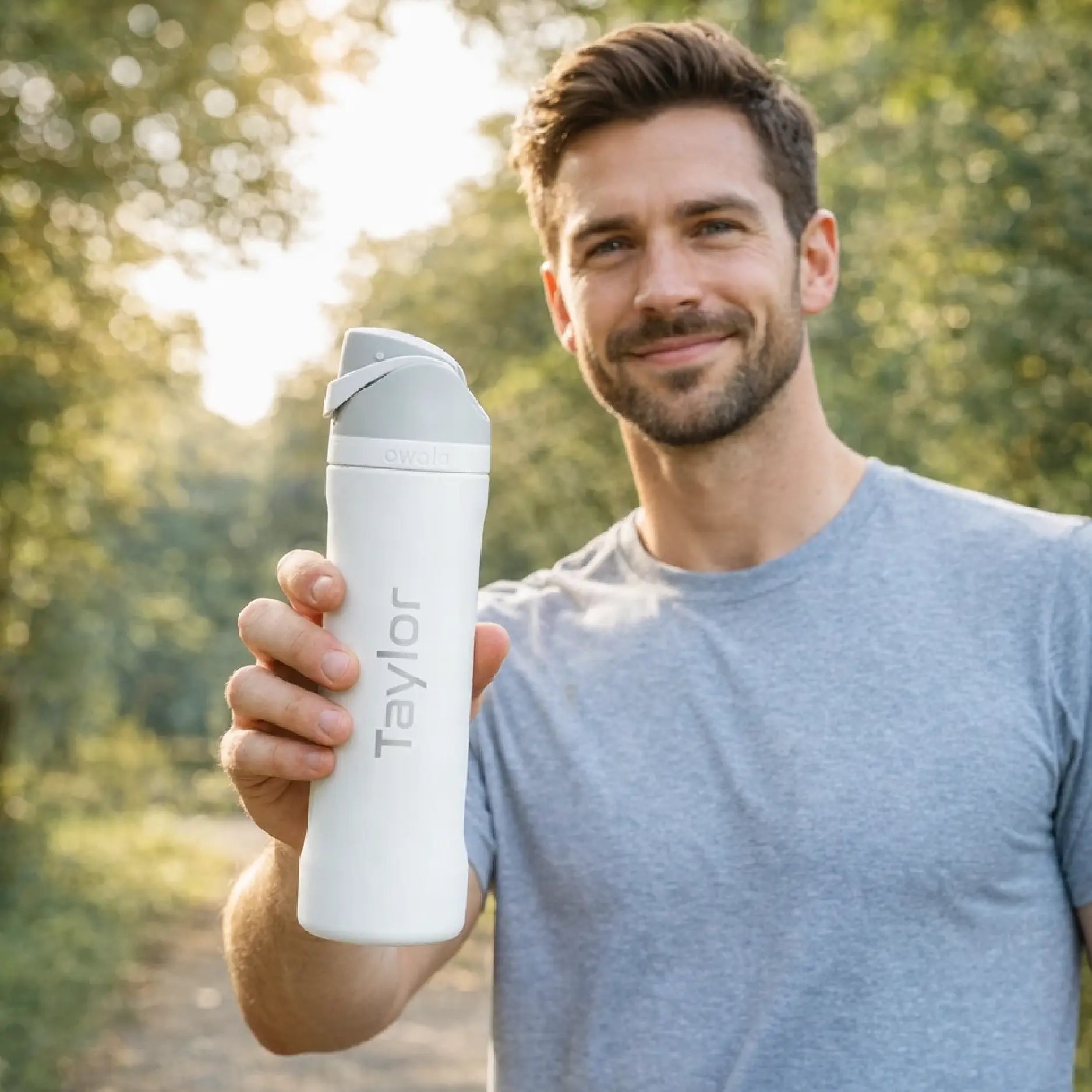 Man holding laser etched white Owala 24 oz water bottle with name laser engraved.