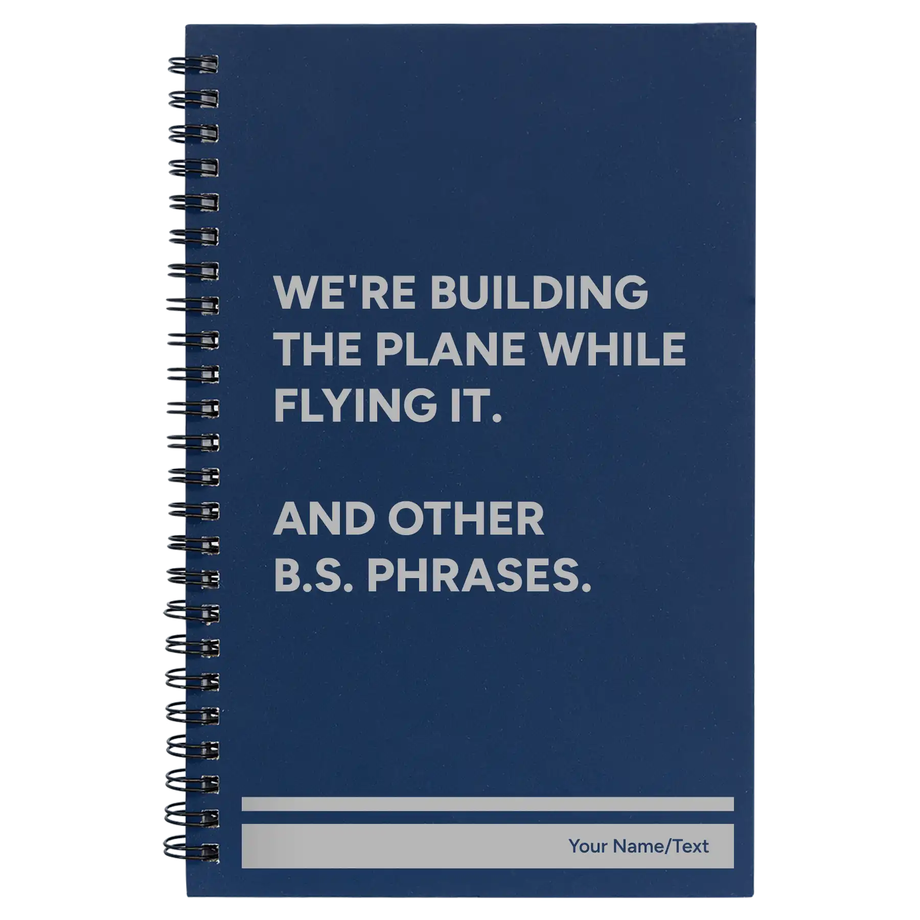 Small blue spiral notebook laser etched with 'We're Building The Plane While Flying It. And Other B.S. Phrases' design